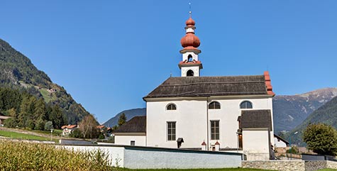 Chiesa di Villa Ottone circondata da prati e montagne