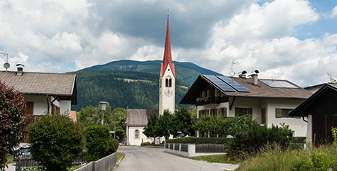 Il paese di Valdaora con campanile che si staglia sulle montagne