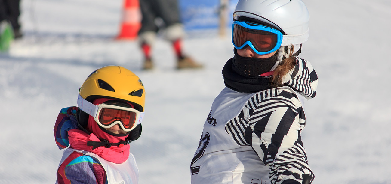 Kinder einer Kinder-Skischule mit Helm und Skifahrerbrille