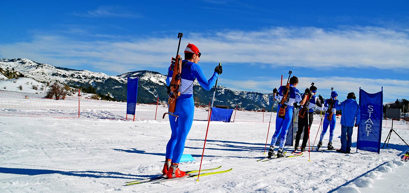 Atleti di biathlon su pista innevata con cielo azzurro