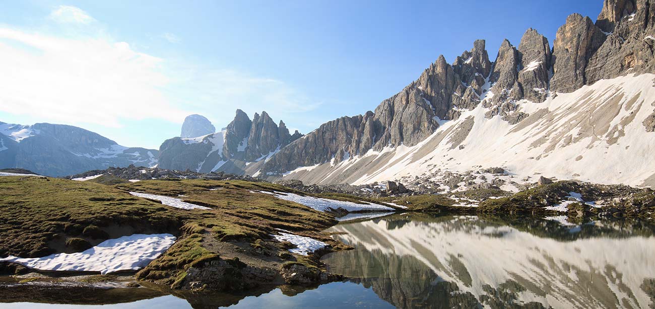 Prato con pozze d'acqua con Dolomiti e cielo azzurro sullo sfondo